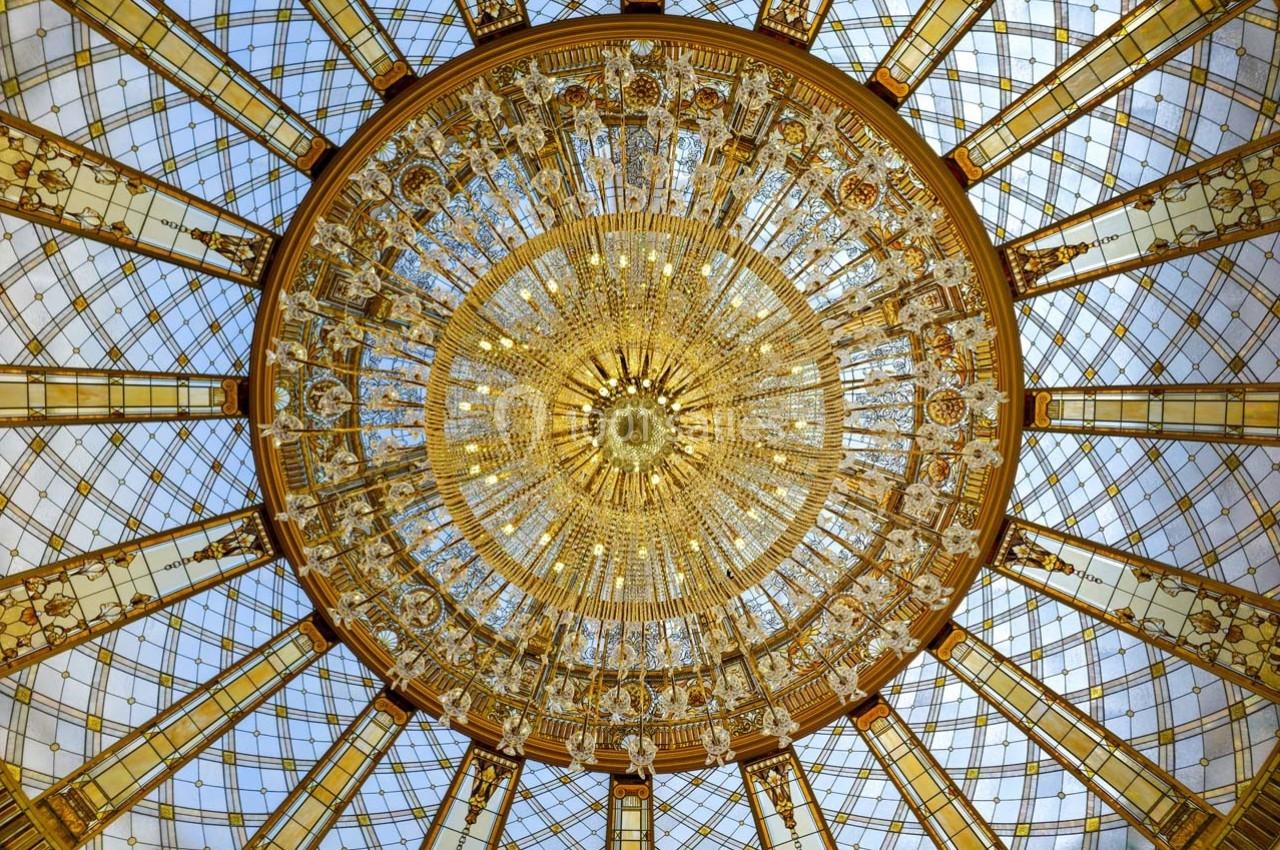 Dôme en verre et métal doré avec motifs décoratifs, vu en contre-plongée, laissant passer la lumière naturelle.