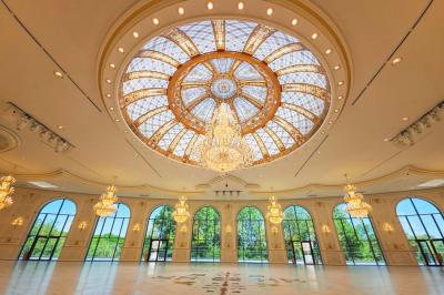 Lustre en cristal doré suspendu sous un plafond peint avec des nuances pastel de bleu et de rose.