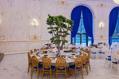 Lustre en cristal doré suspendu sous un plafond peint avec des nuances pastel de bleu et de rose.
