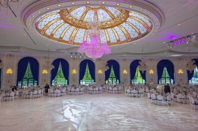 Lustre en cristal doré suspendu sous un plafond peint avec des nuances pastel de bleu et de rose.