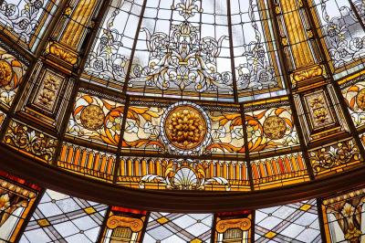 Lustre en cristal doré suspendu sous un plafond peint avec des nuances pastel de bleu et de rose.