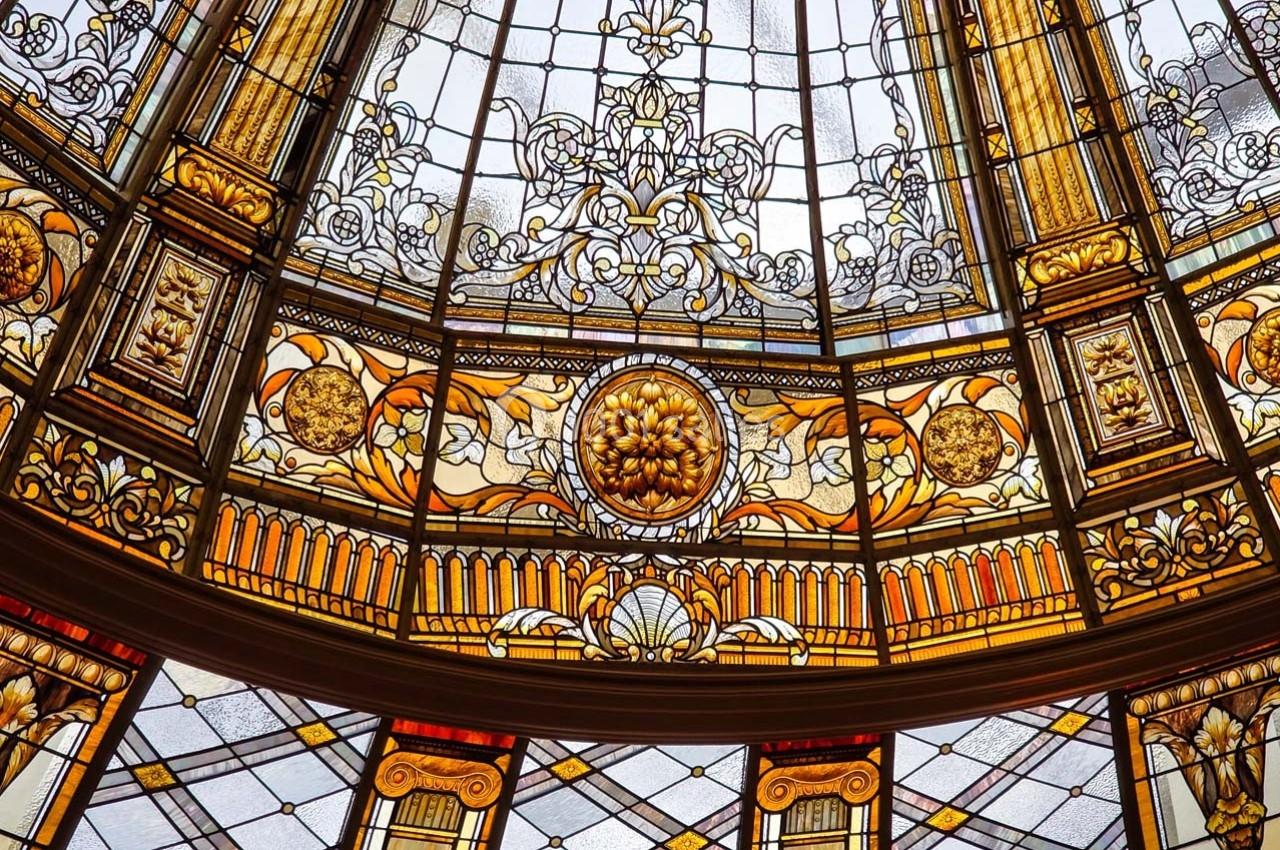 Verrière colorée avec motifs floraux et géométriques, ornée de détails dorés et symétriques.