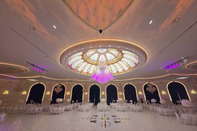 Lustre en cristal doré suspendu sous un plafond peint avec des nuances pastel de bleu et de rose.