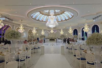 Lustre en cristal doré suspendu sous un plafond peint avec des nuances pastel de bleu et de rose.