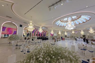 Lustre en cristal doré suspendu sous un plafond peint avec des nuances pastel de bleu et de rose.