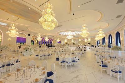 Lustre en cristal doré suspendu sous un plafond peint avec des nuances pastel de bleu et de rose.