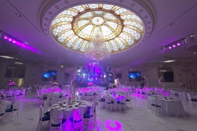 Lustre en cristal doré suspendu sous un plafond peint avec des nuances pastel de bleu et de rose.