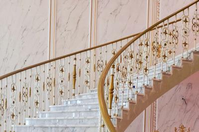 Lustre en cristal doré suspendu sous un plafond peint avec des nuances pastel de bleu et de rose.