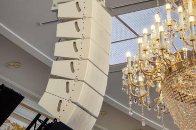 Lustre en cristal doré suspendu sous un plafond peint avec des nuances pastel de bleu et de rose.