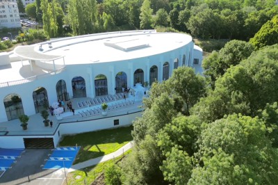 Lustre en cristal doré suspendu sous un plafond peint avec des nuances pastel de bleu et de rose.