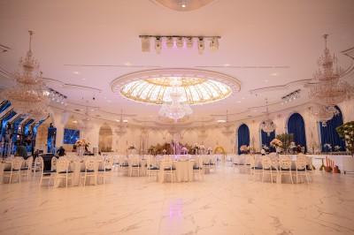 Lustre en cristal doré suspendu sous un plafond peint avec des nuances pastel de bleu et de rose.