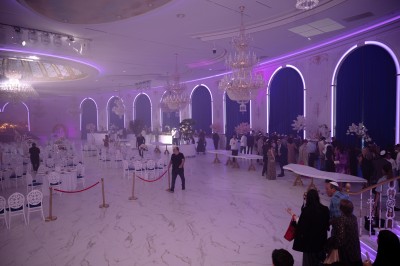 Lustre en cristal doré suspendu sous un plafond peint avec des nuances pastel de bleu et de rose.