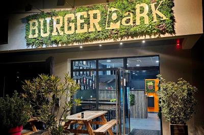 Façade d'un restaurant avec enseigne ’Burger Park’, terrasse en bois et décoration végétale.