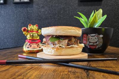 Façade d'un restaurant avec enseigne ’Burger Park’, terrasse en bois et végétation décorative.