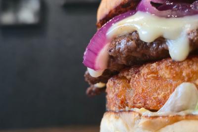 Façade d'un restaurant avec enseigne ’Burger Park’, terrasse en bois et végétation décorative.