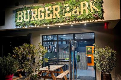 Façade d'un restaurant avec enseigne ’Burger Park’, terrasse en bois et végétation décorative.