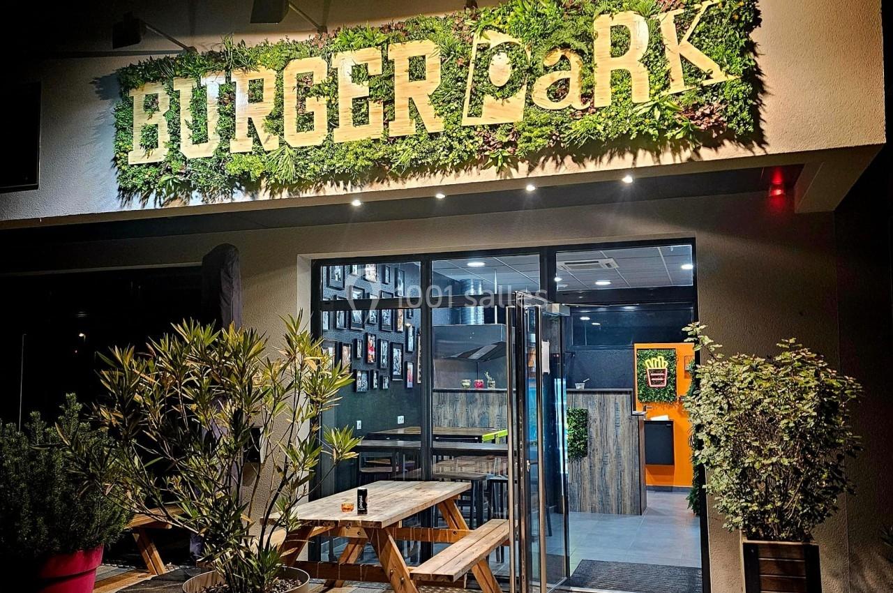 Façade d'un restaurant avec enseigne ’Burger Park’, terrasse en bois et végétation décorative.