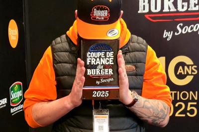 Façade d'un restaurant avec enseigne ’Burger Park’, terrasse en bois et végétation décorative.