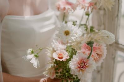 Un couple monte des marches, la mariée en robe blanche et voile, entourée d'invités élégamment vêtus.