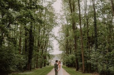 Un couple monte des marches, la mariée en robe blanche et voile, entourée d'invités élégamment vêtus.