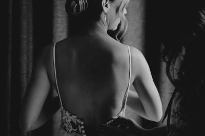 Un couple monte des marches, la mariée en robe blanche et voile, entourée d'invités élégamment vêtus.