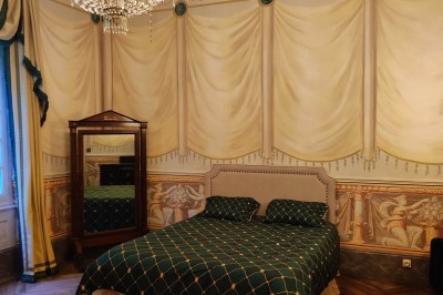 Salle de bain avec baignoire sur pieds, lavabo sur meuble en bois et murs décorés de cadres anciens.