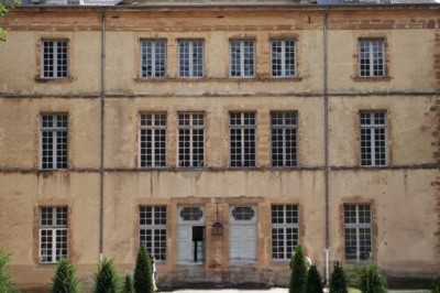 Salle de bain avec baignoire sur pieds, lavabo sur meuble en bois et murs décorés de cadres anciens.
