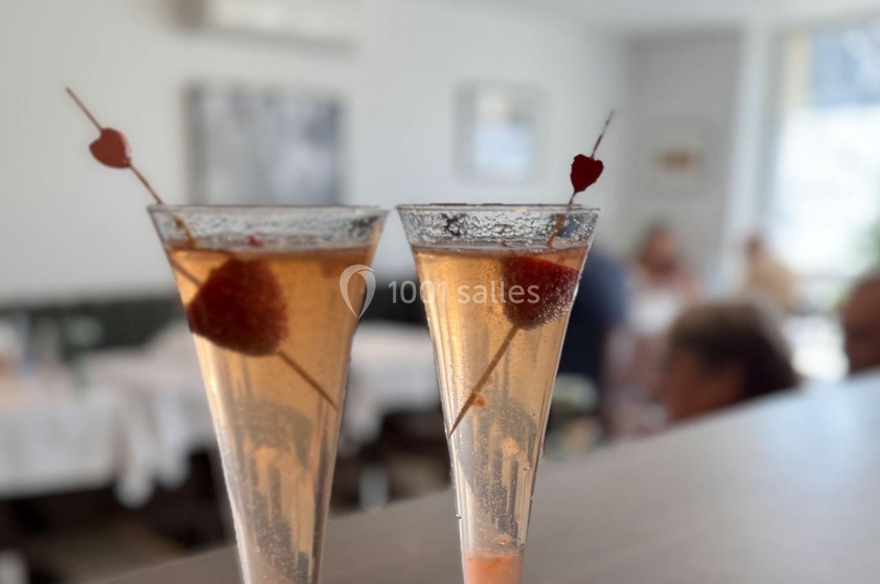 Deux coupes de cocktail pétillant garnies de fraises et de piques décoratives en forme de cœur, dans un restaurant.