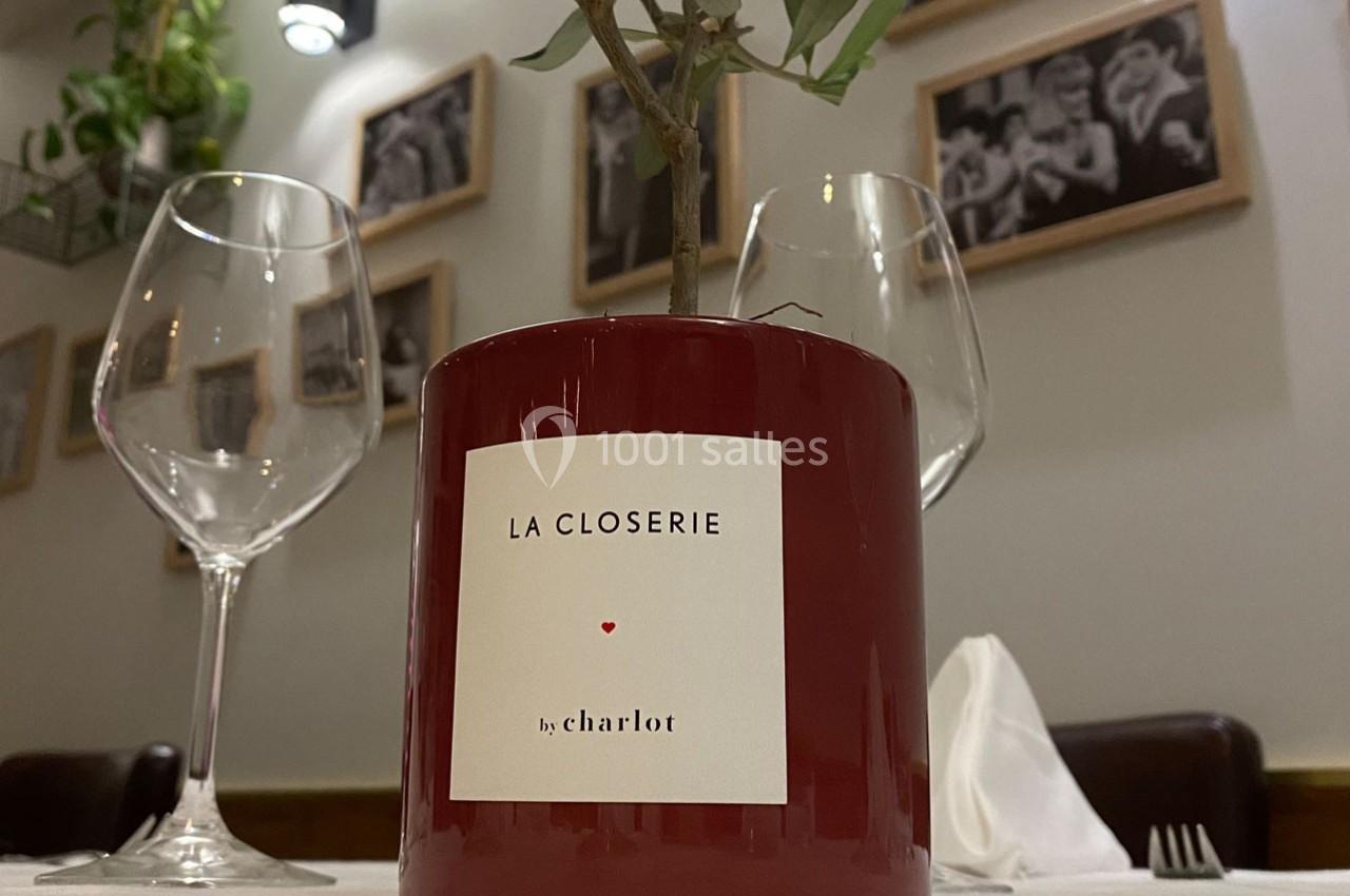Plante en pot rouge avec l'inscription ’La Closerie by Charlot’, posée sur une table dressée dans un restaurant.