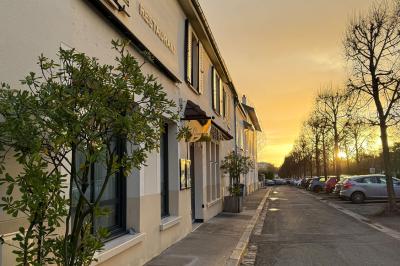 Coucher de soleil illuminant une rue bordée d'arbres et de bâtiments, avec des reflets sur le sol mouillé.