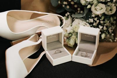 Femme en robe de mariée posant près d'albums photo élégants, entourée de bijoux et d'un décor raffiné.