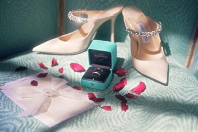 Femme en robe de mariée posant près d'albums photo élégants, entourée de bijoux et d'un décor raffiné.