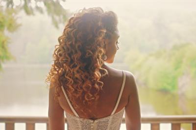 Femme en robe de mariée posant près d'albums photo élégants, entourée de bijoux et d'un décor raffiné.