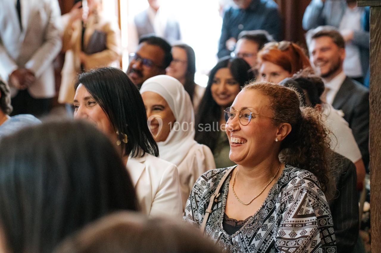 Groupe de personnes assises, souriantes et attentives lors d'un événement en intérieur.