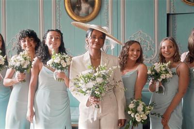 Femme en robe de mariée posant près d'albums photo élégants, entourée de bijoux et d'un décor raffiné.