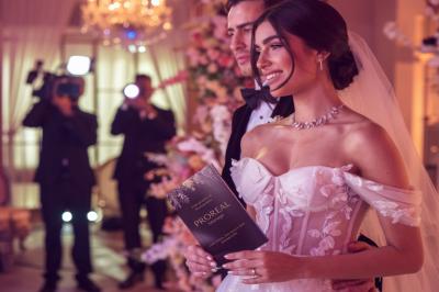 Femme en robe de mariée posant près d'albums photo élégants, entourée de bijoux et d'un décor raffiné.