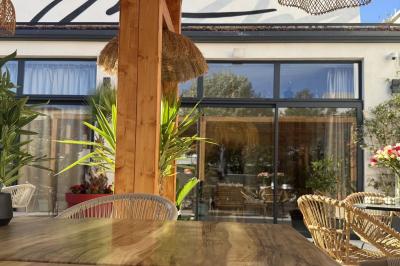 Salle de restaurant lumineuse avec tables dressées, chaises confortables et grandes baies vitrées laissant entrer la lumière…