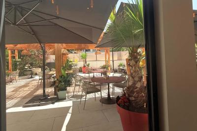 Salle de restaurant lumineuse avec tables dressées, chaises confortables et grandes baies vitrées laissant entrer la lumière…