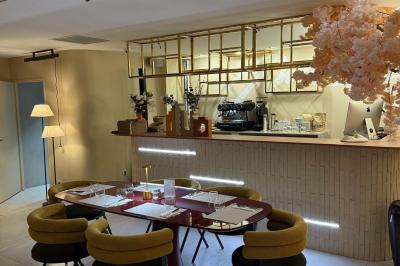 Salle de restaurant lumineuse avec tables dressées, chaises confortables et grandes baies vitrées laissant entrer la lumière…