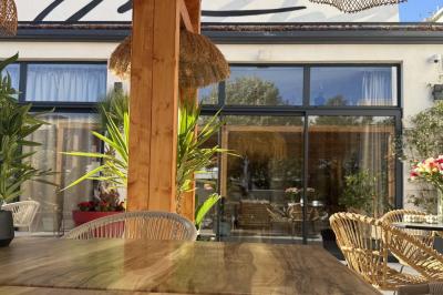 Salle de restaurant élégante avec table dressée, chaises vertes, bar en arrière-plan et décoration florale.