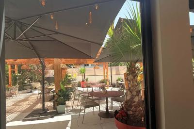 Salle de restaurant élégante avec table dressée, chaises vertes, bar en arrière-plan et décoration florale.