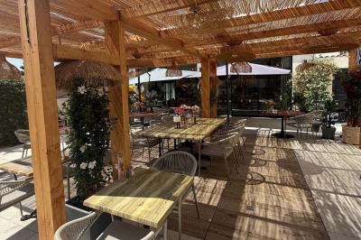 Salle de restaurant élégante avec table dressée, chaises vertes, bar en arrière-plan et décoration florale.