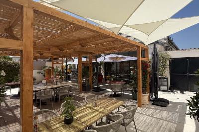 Salle de restaurant élégante avec table dressée, chaises vertes, bar en arrière-plan et décoration florale.