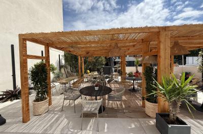 Salle de restaurant élégante avec table dressée, chaises vertes, bar en arrière-plan et décoration florale.