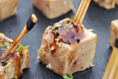 Dessert composé de crème fouettée, framboises fraîches, pétales de fleurs et feuilles de menthe sur une assiette noire.