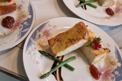 Gâteau décoré de glaçage caramel, éléments en chocolat, framboises et feuilles de menthe sur une assiette blanche.
