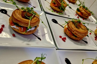 Gâteau décoré de glaçage caramel, éléments en chocolat, framboises et feuilles de menthe sur une assiette blanche.