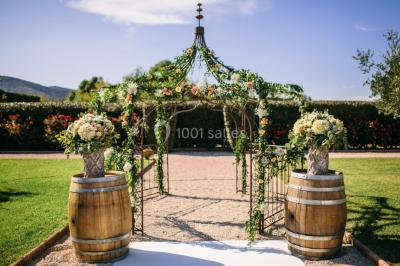 Allée rouge menant à une cérémonie en plein air, entourée de chaises blanches et de jardins verdoyants.