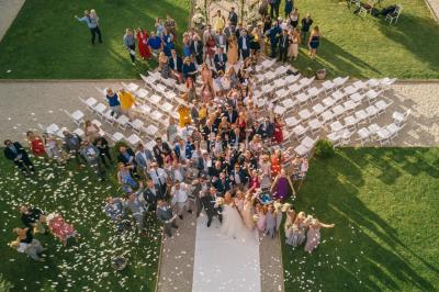 Allée rouge menant à une cérémonie en plein air, entourée de chaises blanches et de jardins verdoyants.
