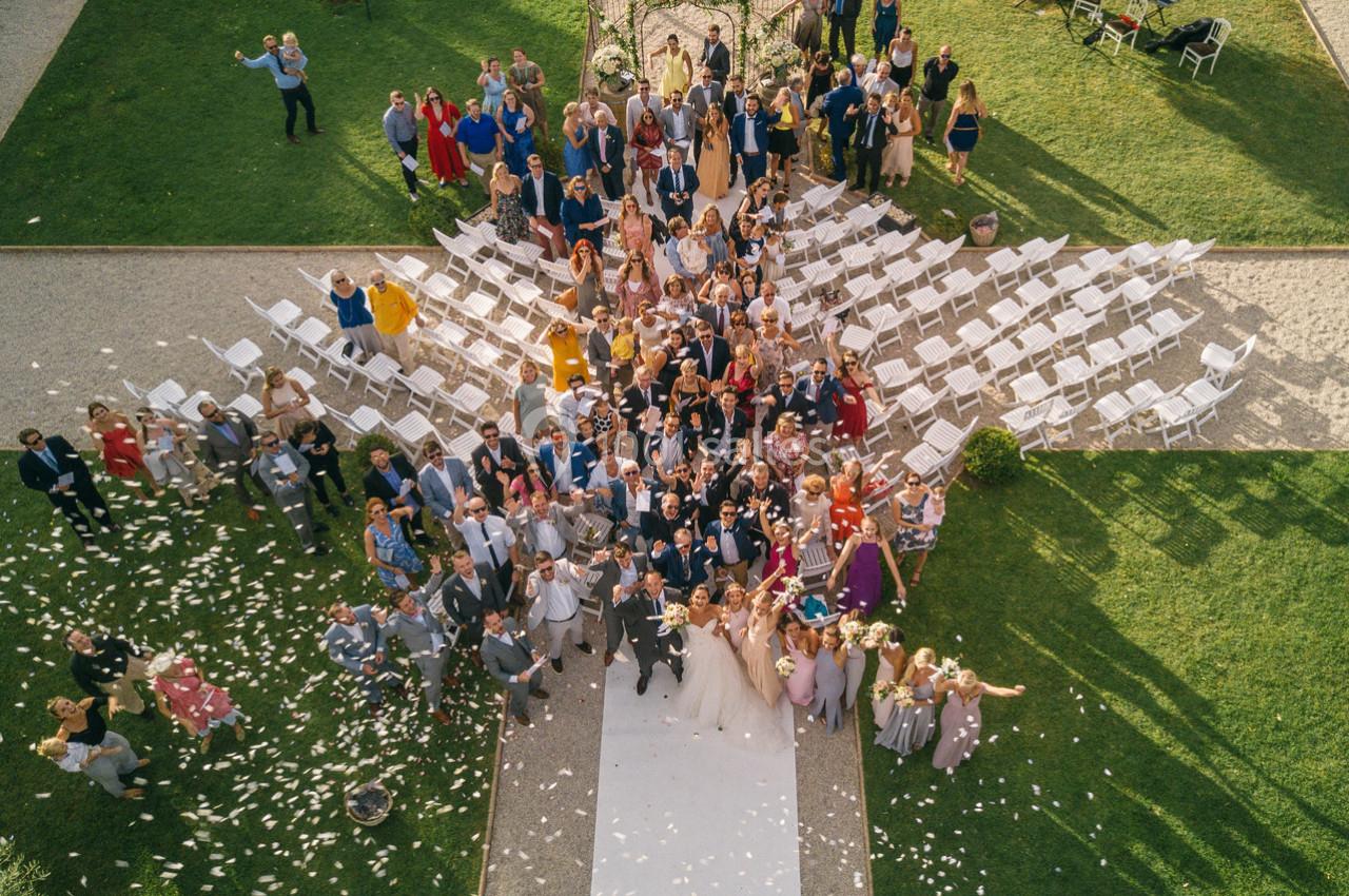 Vue aérienne d'un groupe de personnes rassemblées pour une cérémonie en plein air, entouré de chaises et de pelouse.
